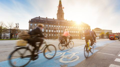 Bicyclists in Copenhagen whiz by Christiansborg Palace.