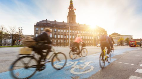 Bicyclists in Copenhagen whiz by Christiansborg Palace. 