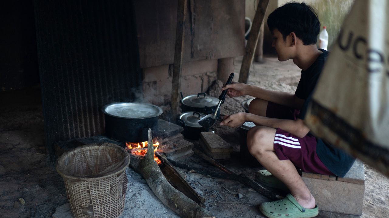 A boy cooks rice in a camp for displaced people in the jungle, in Karen state on January 16, 2023. There is no clean drinking water at the camp, and food is scarce. 