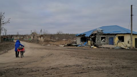 一名婦女騎著自行車穿過烏克蘭東部被毀壞的 Zarichne 村莊。