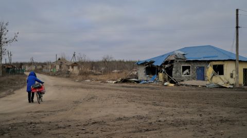 A woman wheels a bicycle through the devastated village of Zarichne, eastern Ukraine.