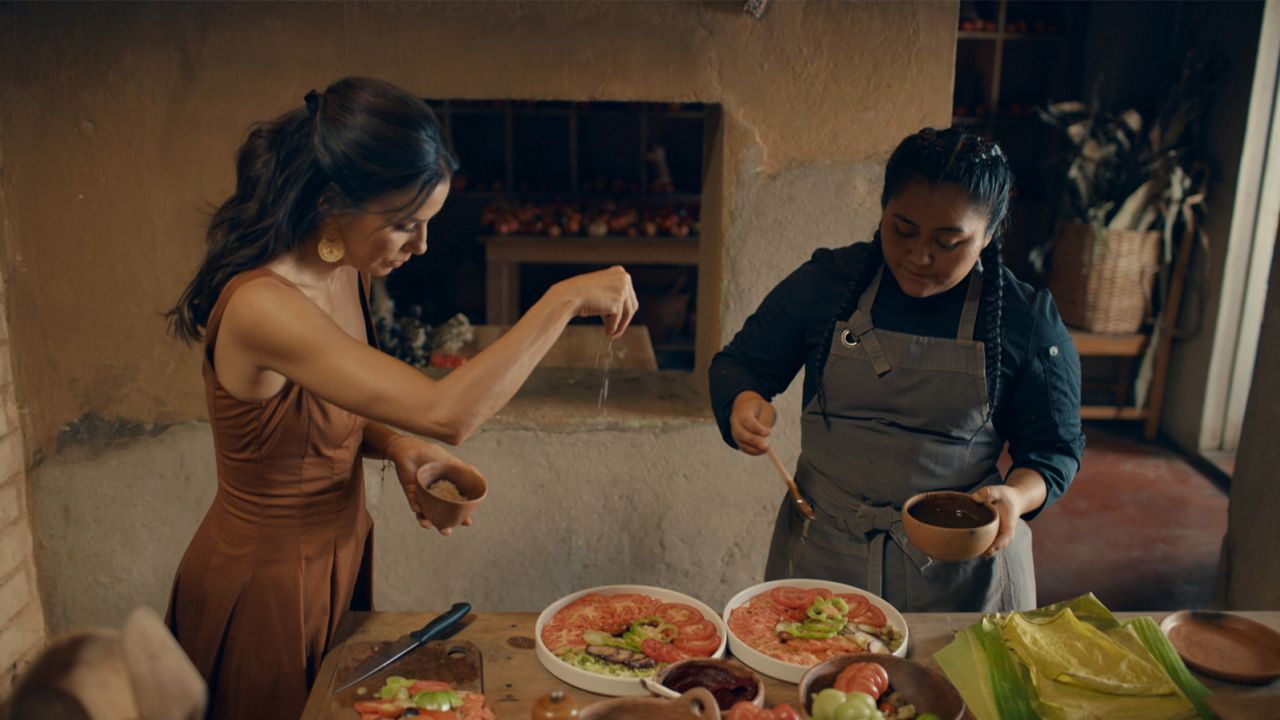 Chef Thalía Barrios García (right) drizzles the salad with the vinaigrette, while Eva Longoria adds flaky salt. 