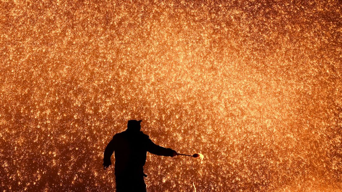 <strong>A wall of lava: </strong>A blacksmith throws molten metal to create a shower of sparks on the eve of the Lantern Festival at a park in Beijing in 2022.  