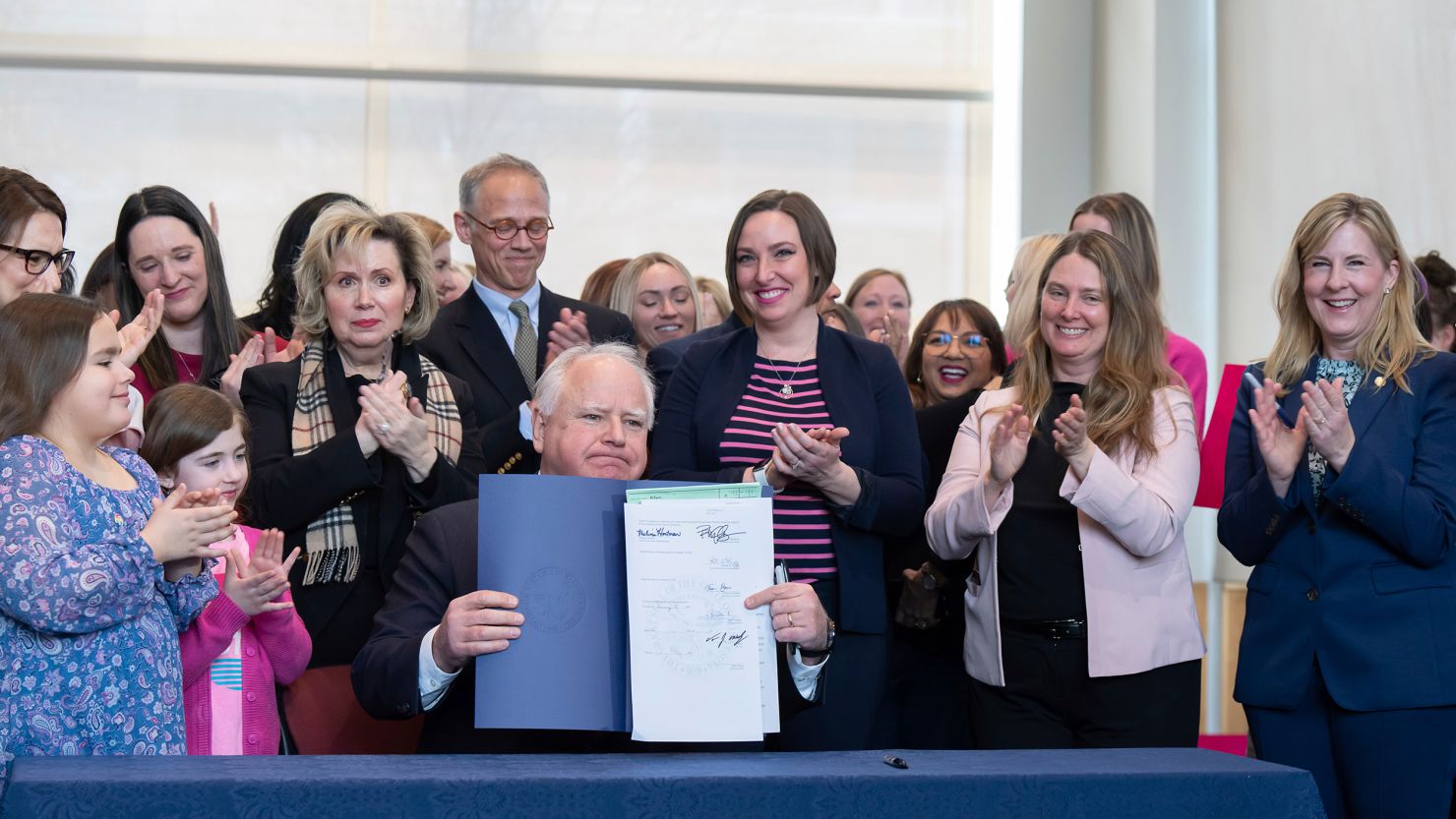 Surrounded by DFL legislators, Minnesota Gov. Tim Walz, center, holds up a bill he signed that adds a "fundamental right" to abortion access into state law on Jan. 31, 2023, in St. Paul, Minn. 