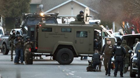 Police check their weapons at a home during a disturbance in Grants Pass, Oregon, on Tuesday.