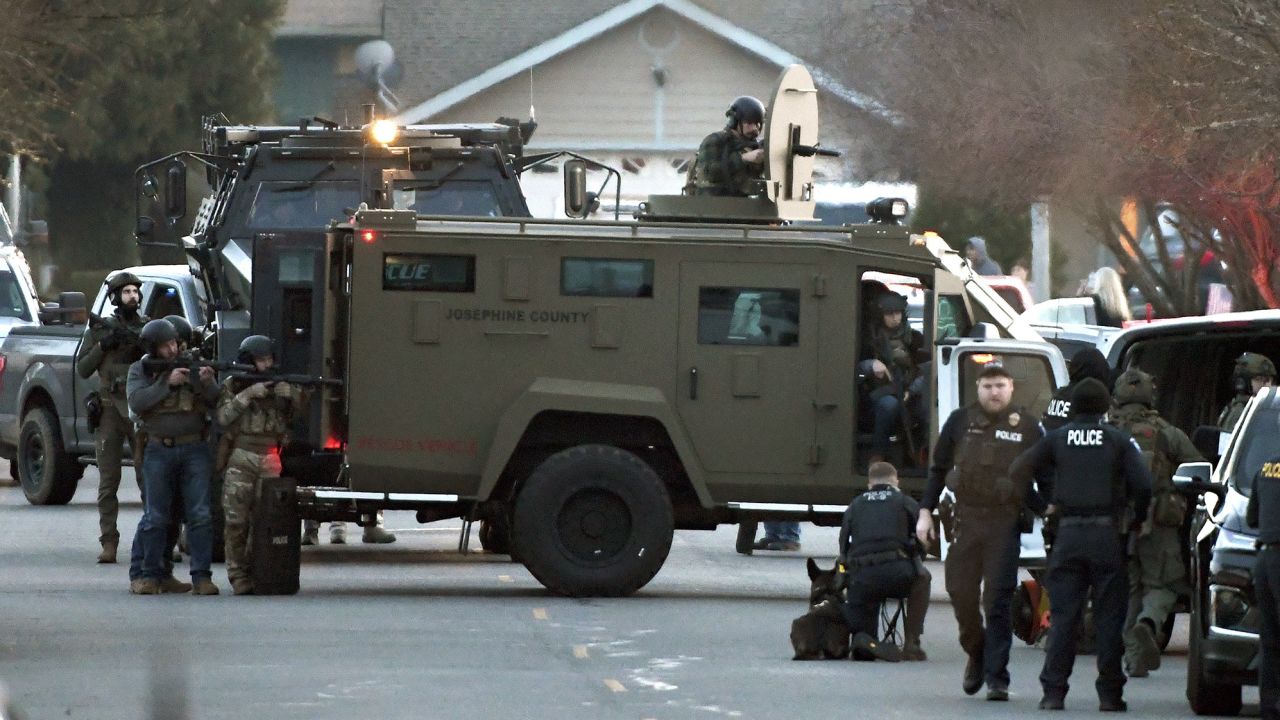 Law enforcement officers aim their weapons at a home during a standoff in Grants Pass, Oregon, on Tuesday.