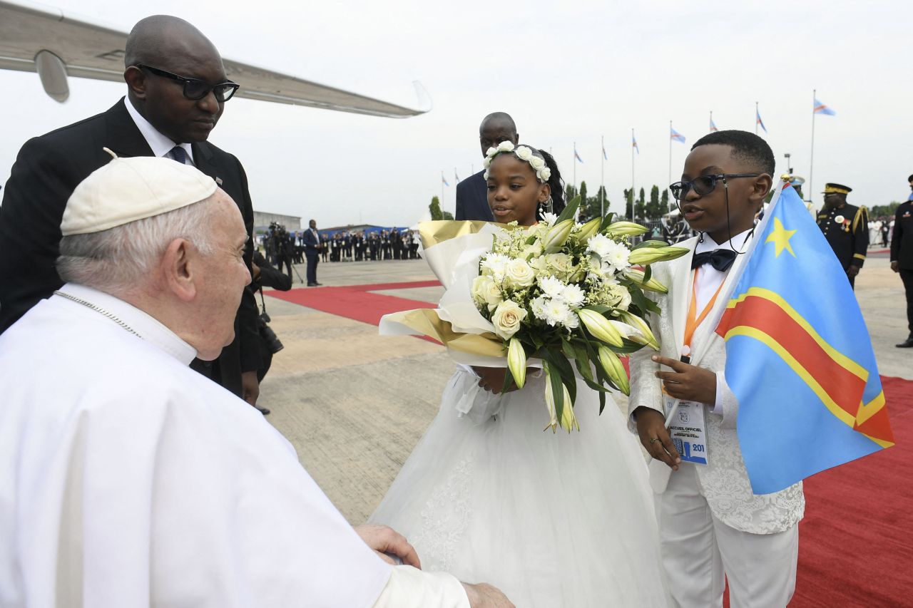 Pope Francis is greeted by two children as he arrives in Kinshasa.