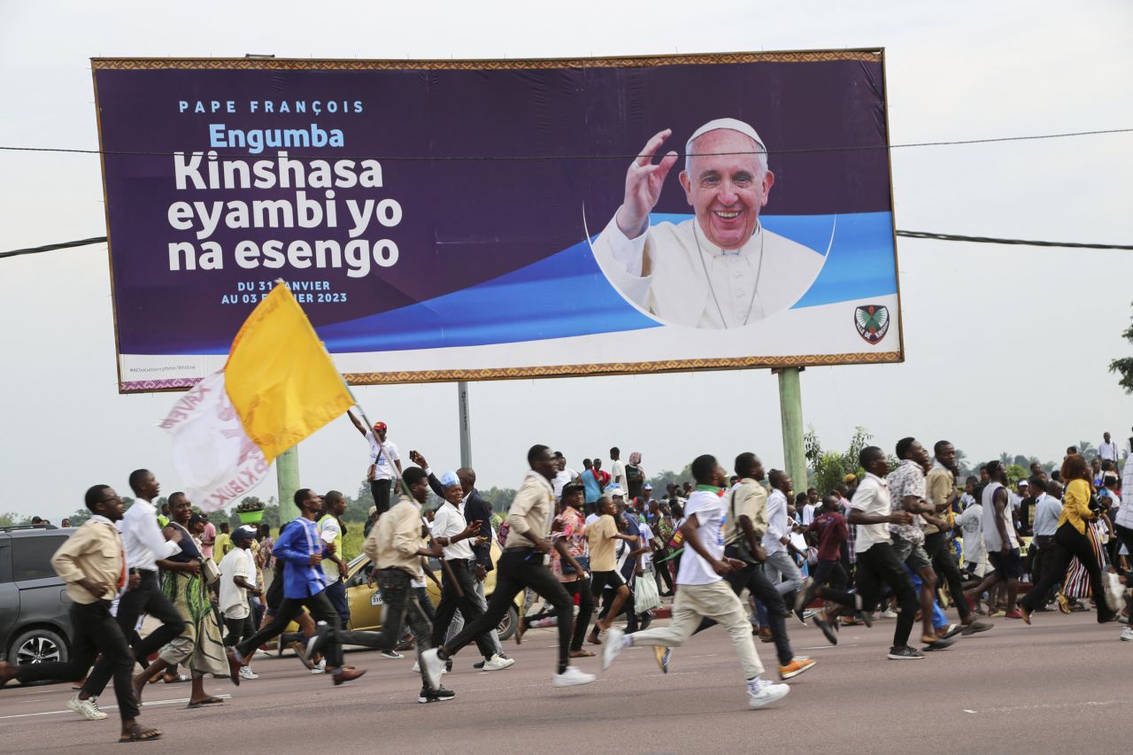 A cheering crowd runs after Pope Francis' convoy as it passes through Kinshasa.