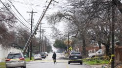 Haley Samford walks past a leaning utility pole on Harmon Avenue in Austin, Texas, during a winter storm on Thursday Feb. 2, 2023. Thousands of frustrated Texans shivered in their homes Thursday after more than a day without power, including many in the state capital, as an icy winter storm that has been blamed for at least 10 traffic deaths lingered across much of the southern U.S.  (Jay Janner/Austin American-Statesman via AP)