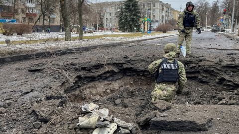 Police officers inspect a crater near the site of a damaged residential building on February 2 amid Russia's repeated attacks on Kramatorsk.