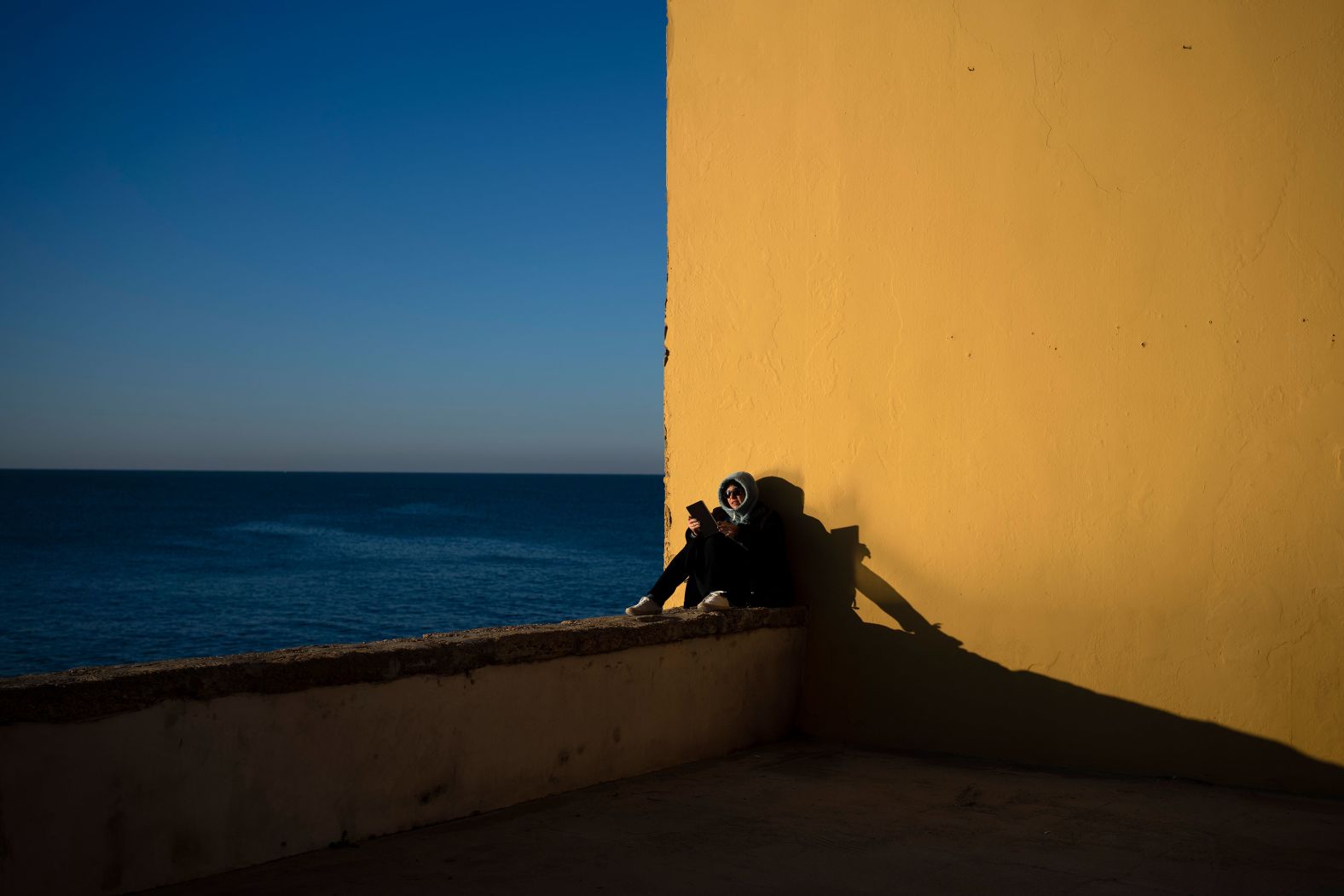 A woman reads by the sea in Cádiz, Spain, early on Friday, January 27.