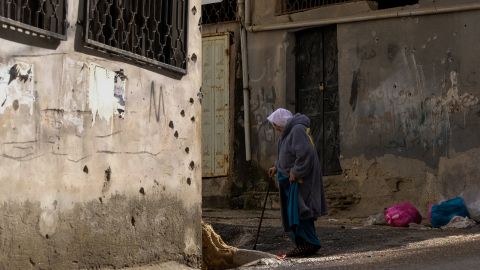 An elderly woman walks near the scene of the raid.