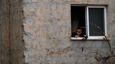 Seorang anak bermain di dekat jendela, di samping bangunan yang hancur.