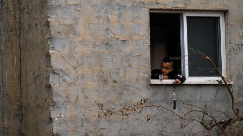 A child plays by a window, next to the building that was destroyed.