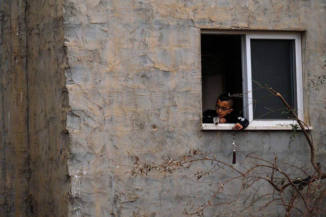 A child plays by a window, next to the building that was destroyed.