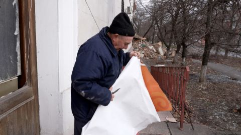 Anatoly cuts sheet plastic to cover his windows that have been destroyed by shelling. 