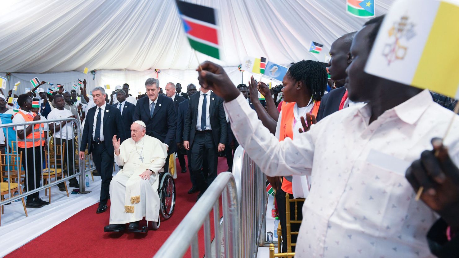 Attendees cheer as Pope Francis, seated on a wheelchair, arrives for a meeting with internally displaced persons at the Freedom Hall in Juba, South Sudan, on February 4, 2023.