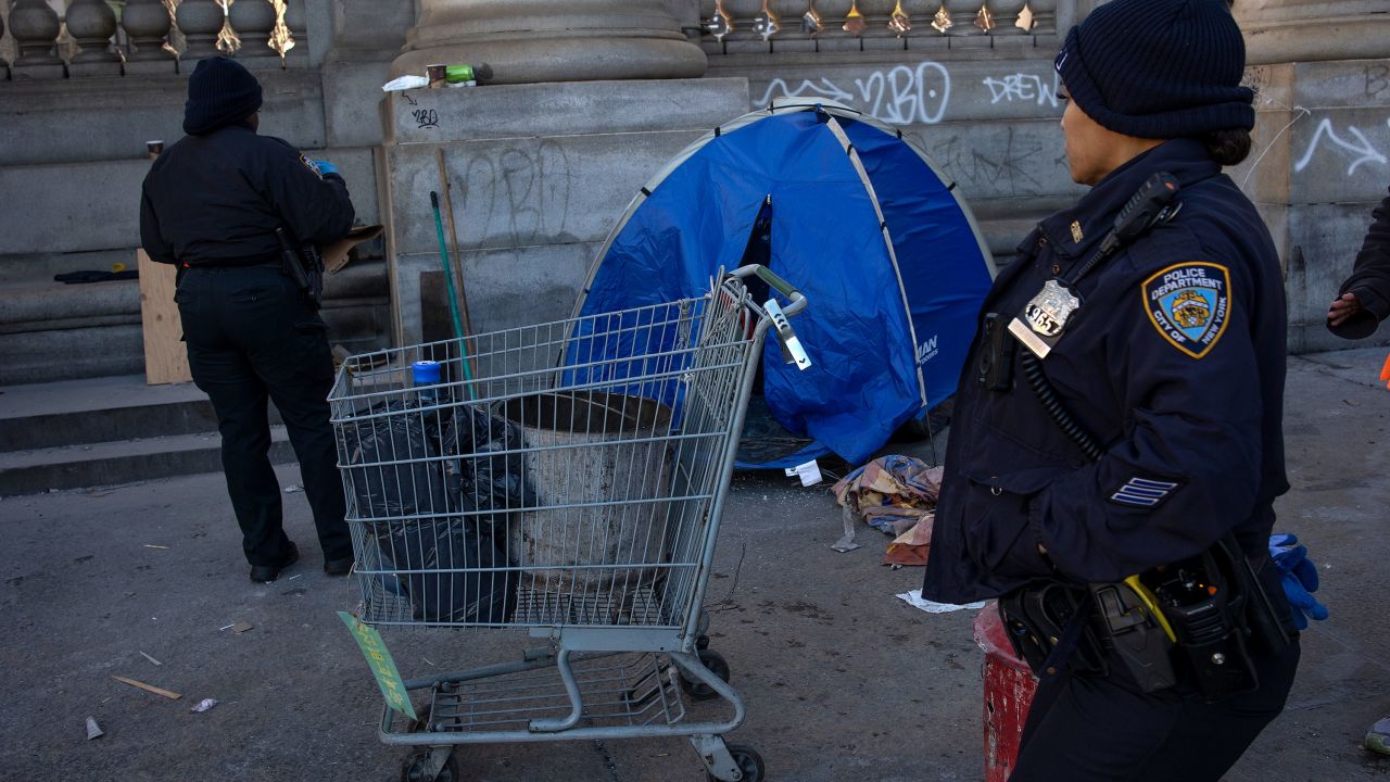 Police officers and sanitation crews force a small group of homeless at an encampment at the base of the Manhattan Bridge to move their belongings during a sweep, Dec. 13, 2022, in New York City.