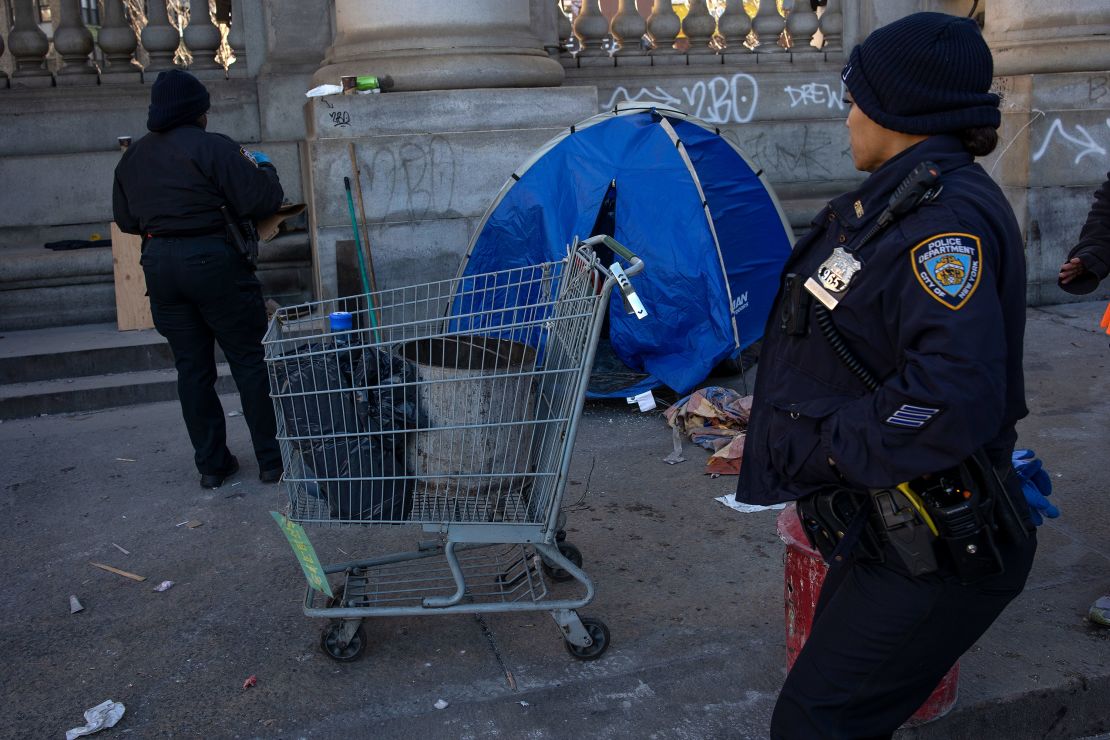Police officers and sanitation crews force a small group of homeless at an encampment at the base of the Manhattan Bridge to move their belongings during a sweep, Dec. 13, 2022, in New York City.