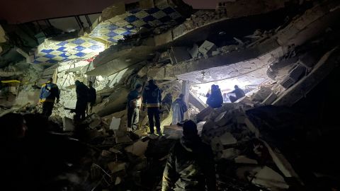 Syrian rescuers (White Helmets) and civilians search for victims and survivors amid the rubble of a collapsed building, in the rebel-held northern countryside of Syria's Idlib province on the border with Turkey, early on February 6, 2023.