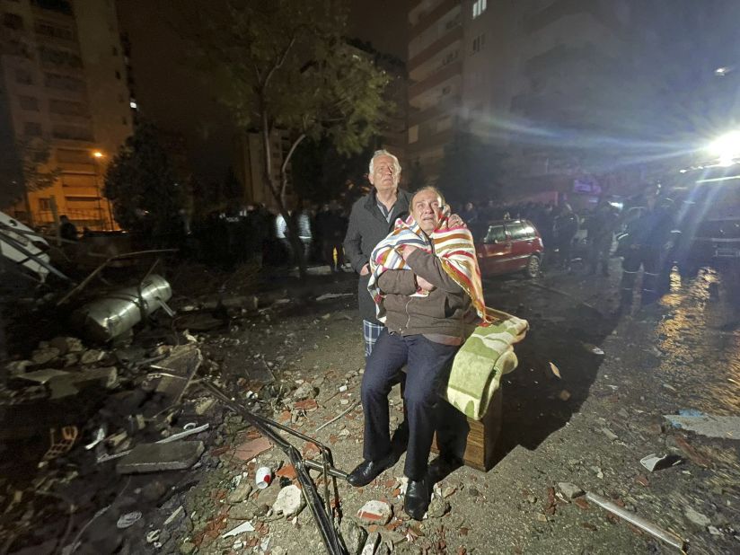 People look on at the site of a destroyed building in Adana. 