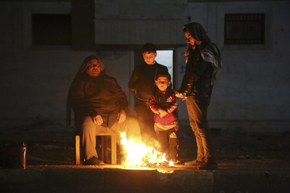 People warm themselves outside of earthquake-affected areas in Aleppo on February 6.