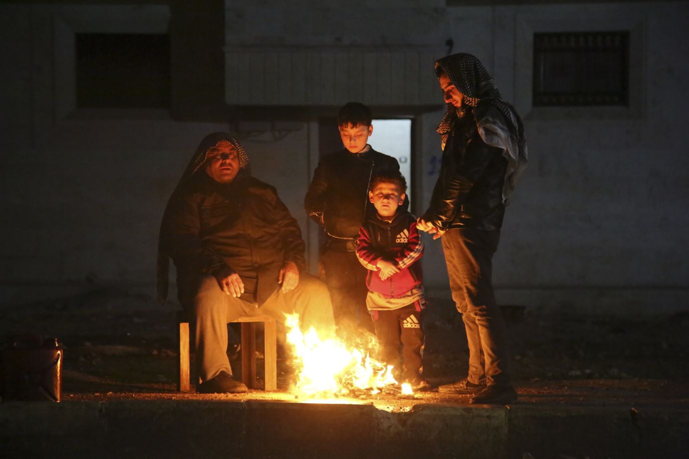 People warm themselves outside of earthquake-affected areas in Aleppo on February 6.