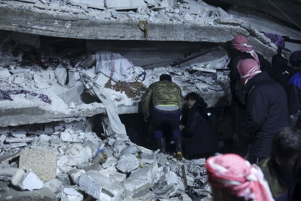 People search under the rubble of a building that collapsed in Azmarin, Syria.