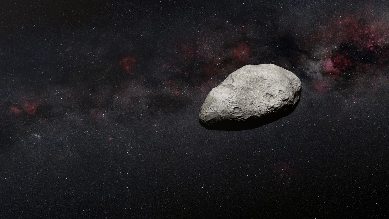 This artist's impression shows an irregularly shaped gray asteroid against a dark background.