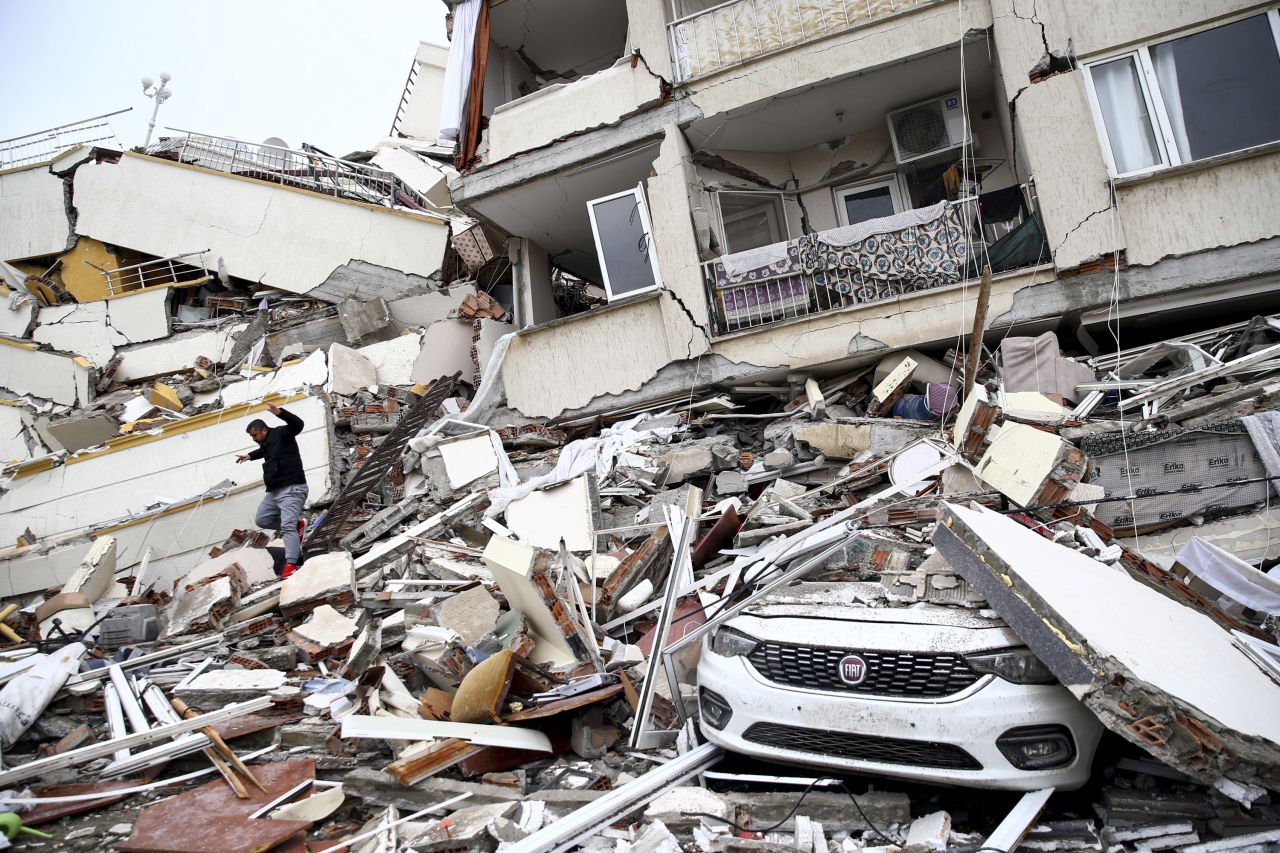 A person climbs through the rubble of a collapsed building in Hatay.