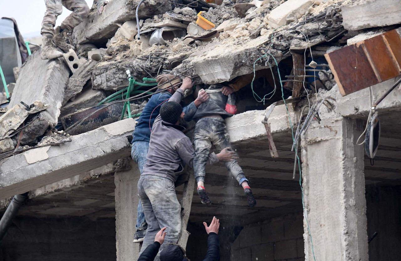 Residents rescue an injured girl from the rubble of a collapsed building in Jandaris on February 6.