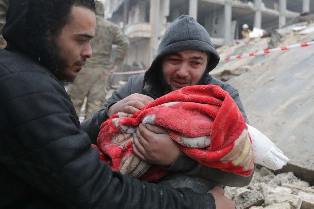 A man weeps as he carries the body of his infant son who was killed in Jandaris.