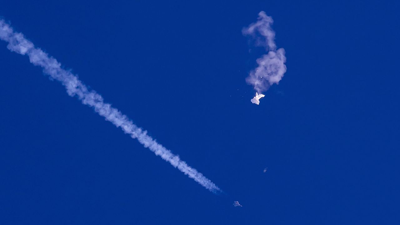 In this photo provided by Chad Fish, the remnants of a large balloon drift above the Atlantic Ocean, just off the coast of South Carolina, with a fighter jet and its contrail seen below it, Feb. 4, 2023. The downing of the suspected Chinese spy balloon by a missile from an F-22 fighter jet created a spectacle over one of the state's tourism hubs and drew crowds reacting with a mixture of bewildered gazing, distress and cheering. (Chad Fish via AP, File)
