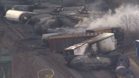 Derailed train cars smoldered Monday in East Palestine, Ohio.