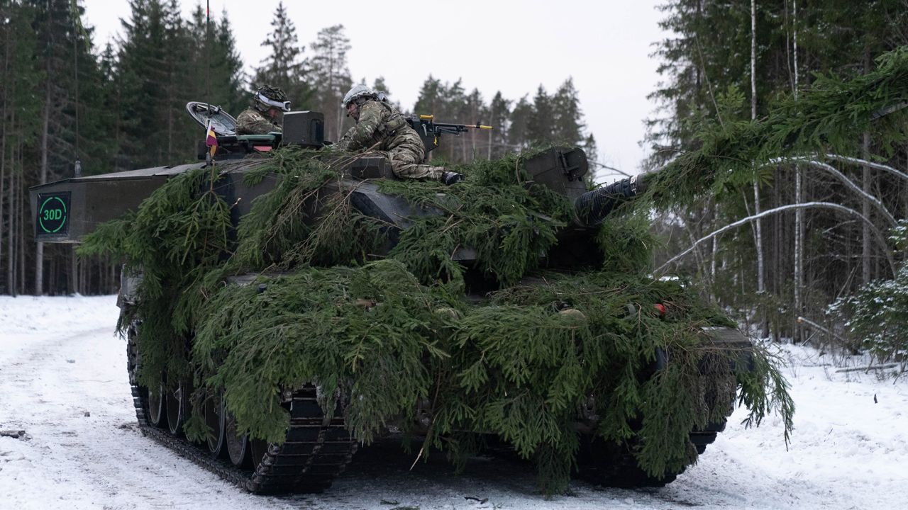 A British tank commander passes orders to the crew of his Challenger 2 tank, in NATO exercises in Estonia.