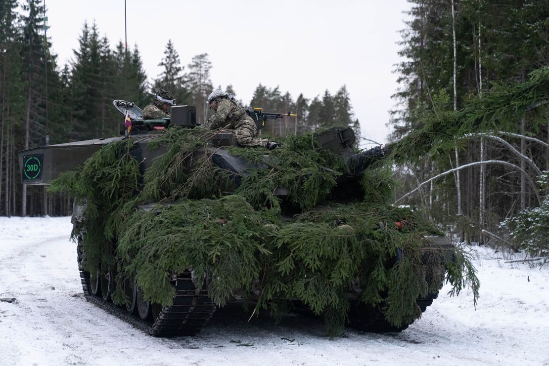 A British tank commander passes orders to the crew of his Challenger 2 tank, in NATO exercises in Estonia.
