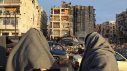 People wrapped in blankets look at the rubble as the search for survivors continues in the aftermath of the earthquake, in Aleppo, Syria, on Tuesday. 
