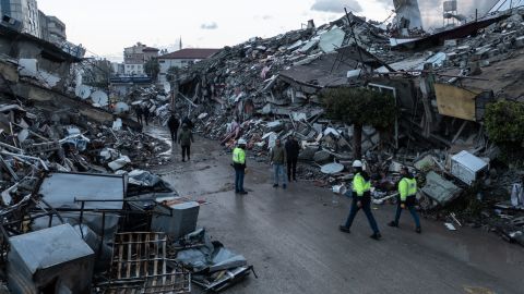 People walk past destroyed buildings in Iskenderun, Turkey, on Tuesday.