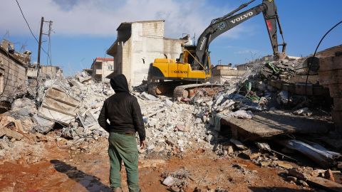 A Syrian boy watches as an excavator goes through the rubble of a house in which an entire family except a newborn baby was killed, on February 7, 2023, in the Syrian town of Jandaris.