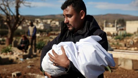 A man carries the body of a family member who died in the quake, at a cemetery in the town of Jinderis, Aleppo province, Syria, Tuesday, Feb. 7, 2023. 