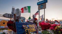People pray and pay their respects at the makeshift memorial for victims of the shooting that left a total of 22 people dead at the Cielo Vista Mall WalMart (background) in El Paso, Texas, on August 6, 2019. 
