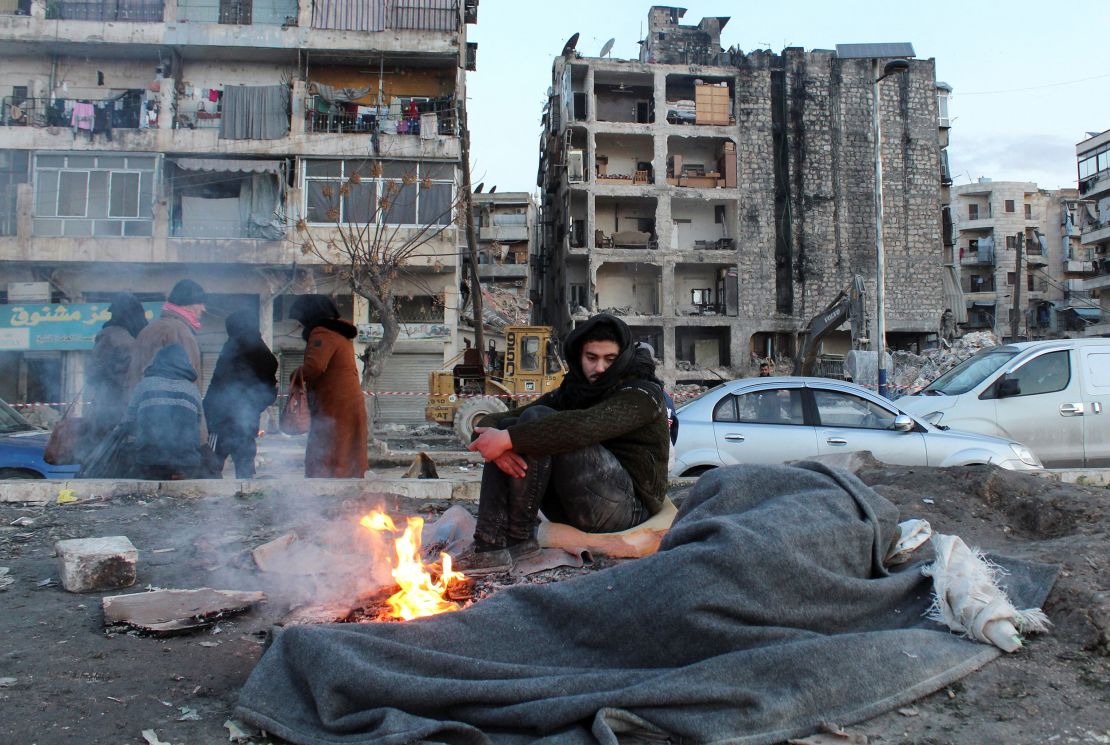 A man who evacuated his home warms up next to a fire in the aftermath of the earthquake, in Aleppo, Syria, February 8, 2023. 