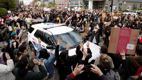 Ohio State students surround a police vehicle on April 21, 2021, while marching toward the Ohio Statehouse to protest the police shooting that killed Ma'Khia Bryant.