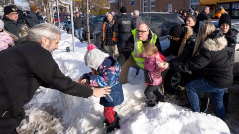 Parents and their children are loaded onto a warming bus as they wait for news after a bus crashed into a day care center in Laval, Quebec, on February 8, 2023.