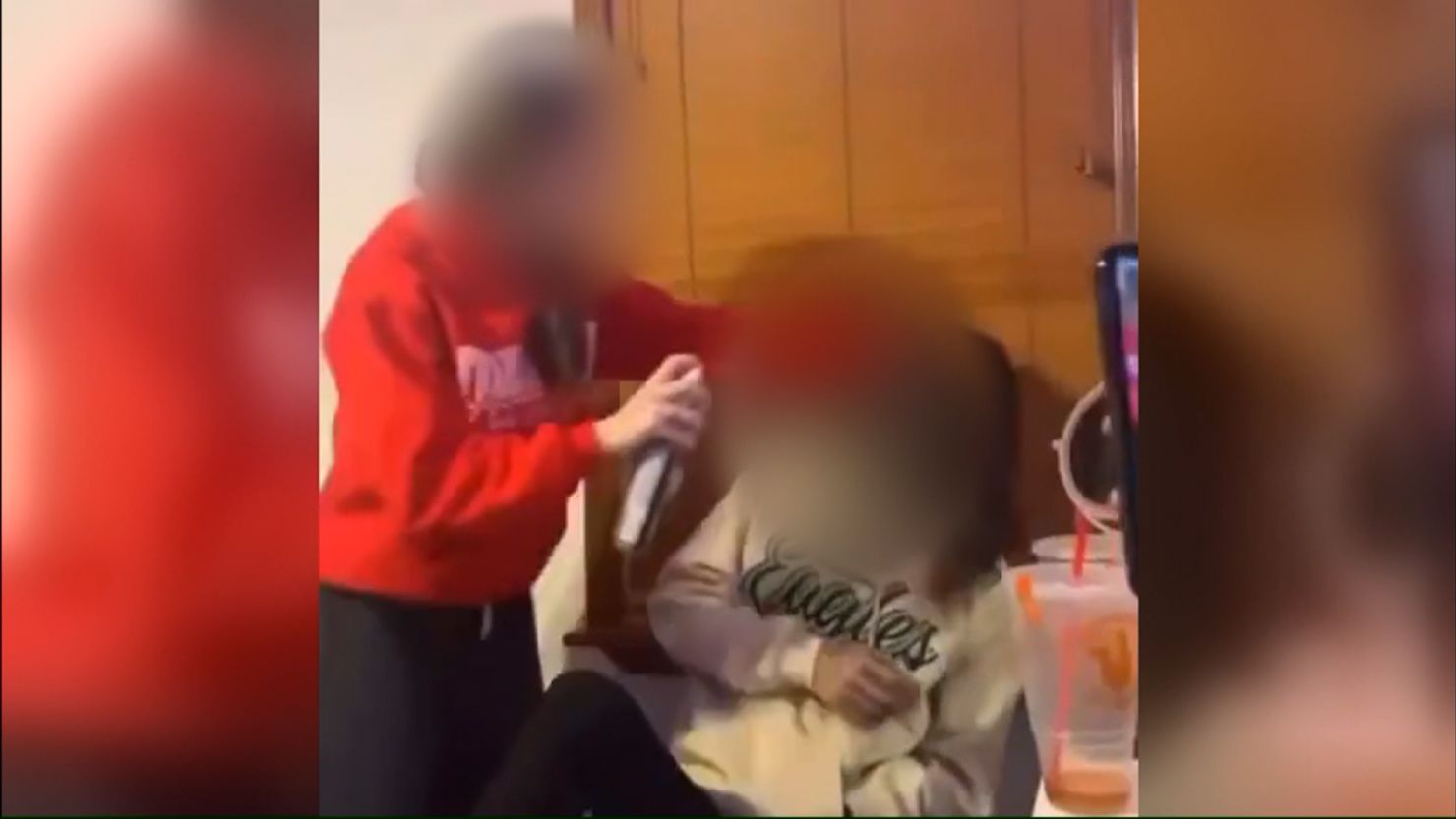 A screenshot from a video that circulated online Tuesday showing a student using black spray paint on another student's face. 