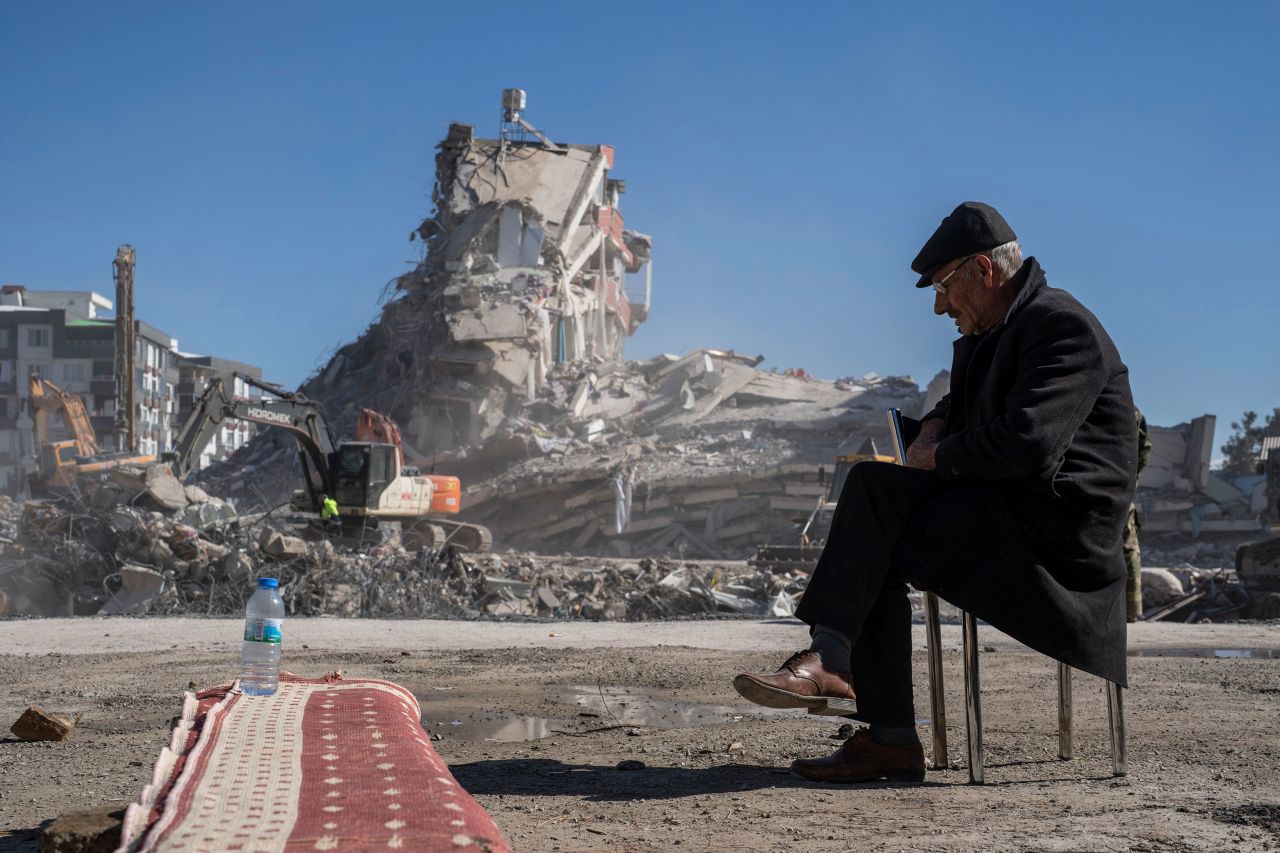 Mehmet Nasir Duran sits on a chair as heavy machines remove debris from a building where five of his family members were trapped in Nurdagi, Turkey, on February 9.