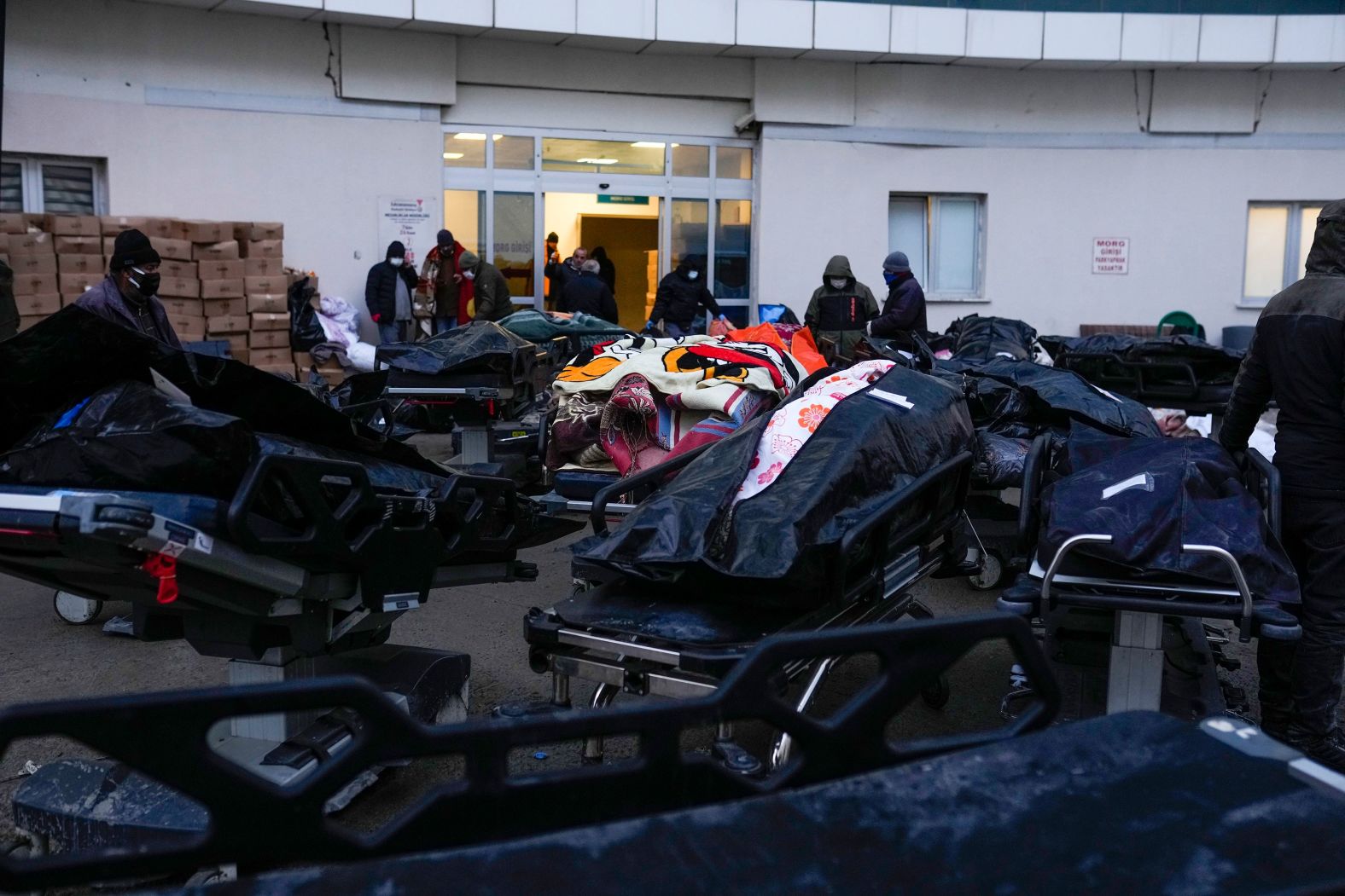 People stand next to the dead bodies of earthquake victims in Elbistan on February 9.