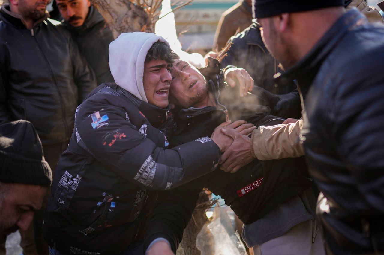 A man, center, reacts after rescue team members removed the dead body of his father in Elbistan.