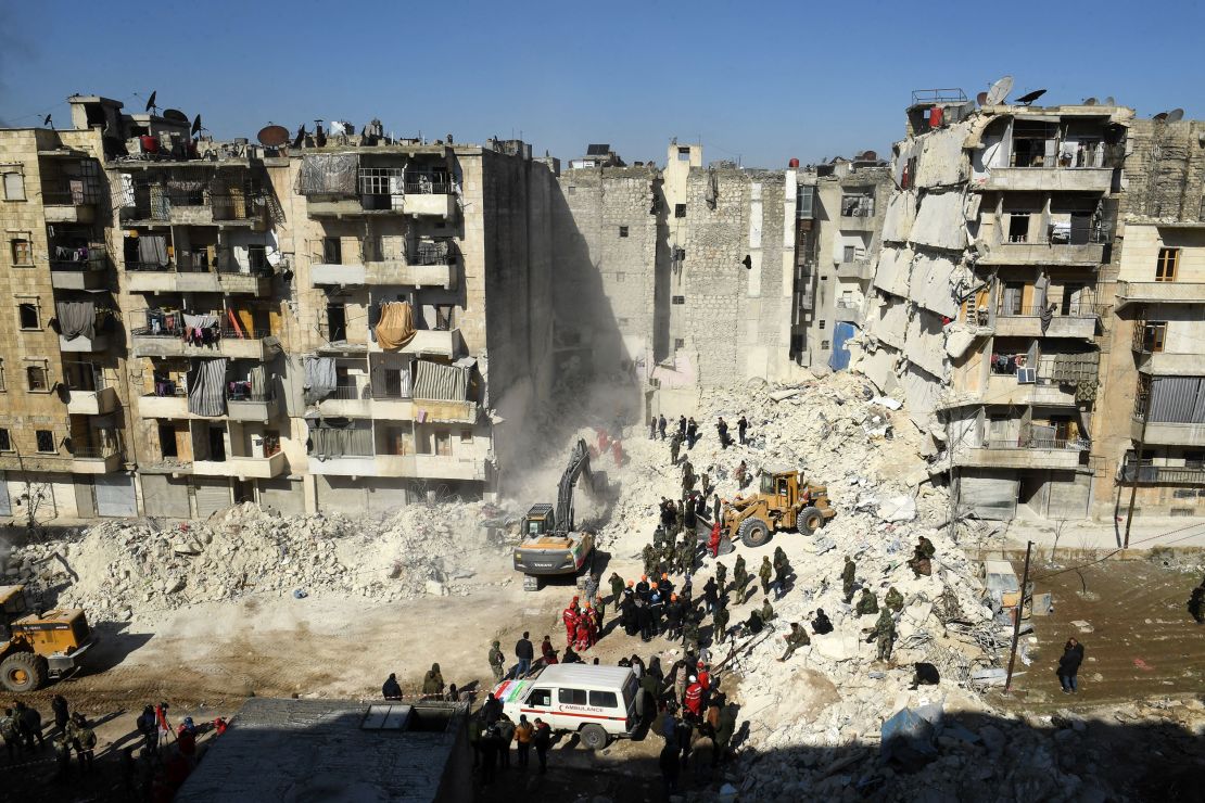  Syrian soldiers look on as rescuers use heavy machinery sift through the rubble of a collapsed building in the northern city of Aleppo on February 9, 2023. 