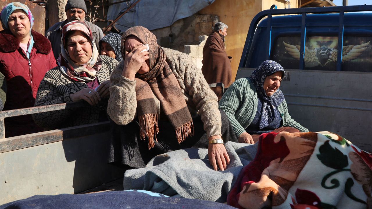 Syrian women weep next to bodies lying on the back of a truck on February 7, 2023, in the town of Jandaris, in the rebel-held part of Aleppo province.